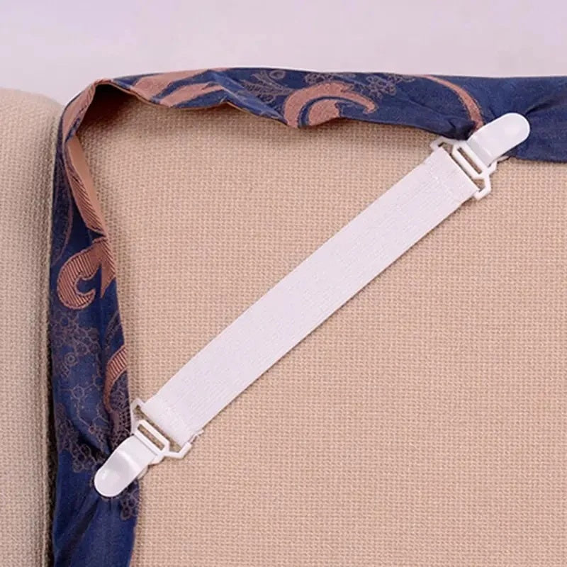 Bed sheet holder clipped across a fitted sheet corner under a mattress